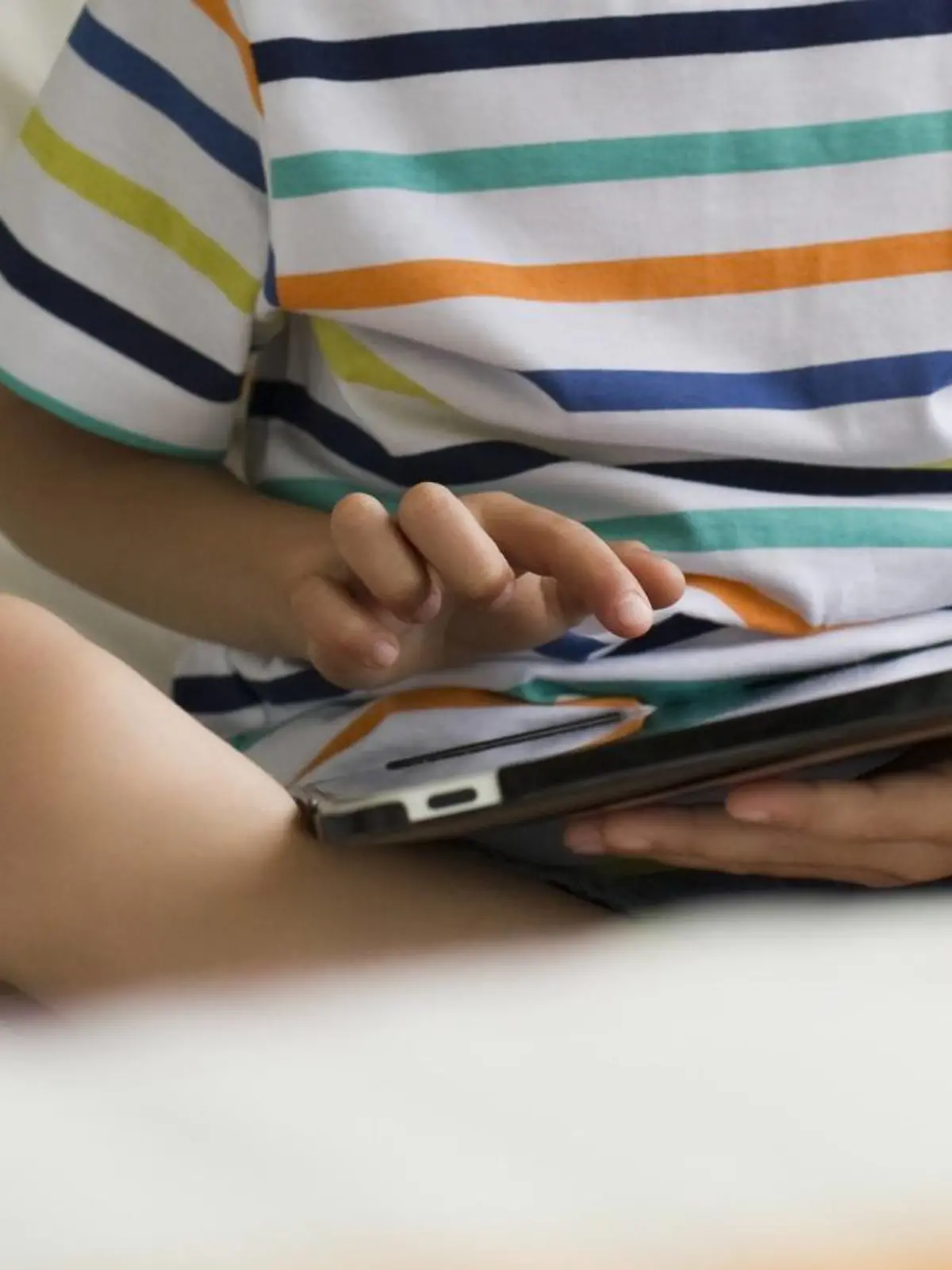 Boy sitting on bed, using digital tablet PUBLICATIONxINxGERxSUIxAUTxONLY Copyright: EricxAudras B11258111  