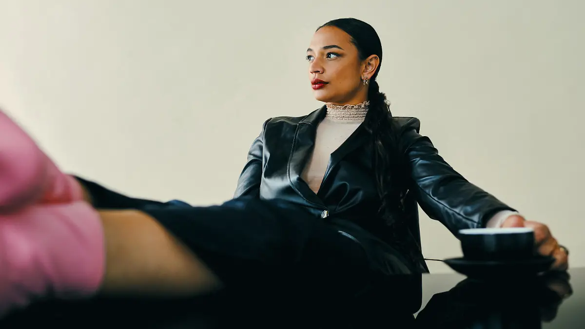 Studio shot of a beautiful young woman sitting with her feet up on a table against a brown background