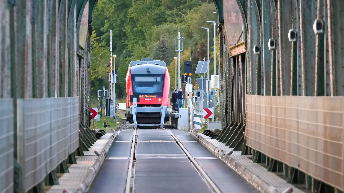 PRODUKTION - 25.09.2022, Schleswig-Holstein, Boren: Ein Regionalzug wartet am Behelfsbahnhof vor der Lindaunisbrücke auf Fahrgäste. Normalerweise fahren Züge über die Schleibrücke bei Lindaunis. Seit Mitte September aber heißt es für Fahrgäste: Austeigen und zu Fuß die Schlei passieren. Wegen Bauarbeiten ist die Brücke über die Schlei bei Lindaunis für Autos und Züge gesperrt. Foto: Jonas Walzberg/dpa +++ dpa-Bildfunk +++