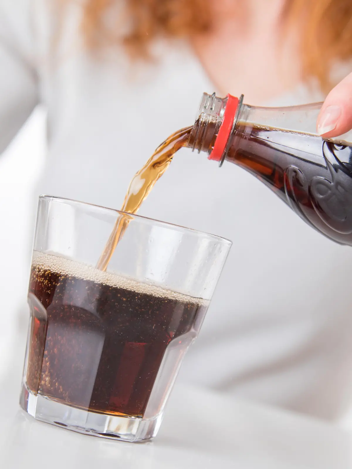 Frau gießt sich Cola in ein Glas