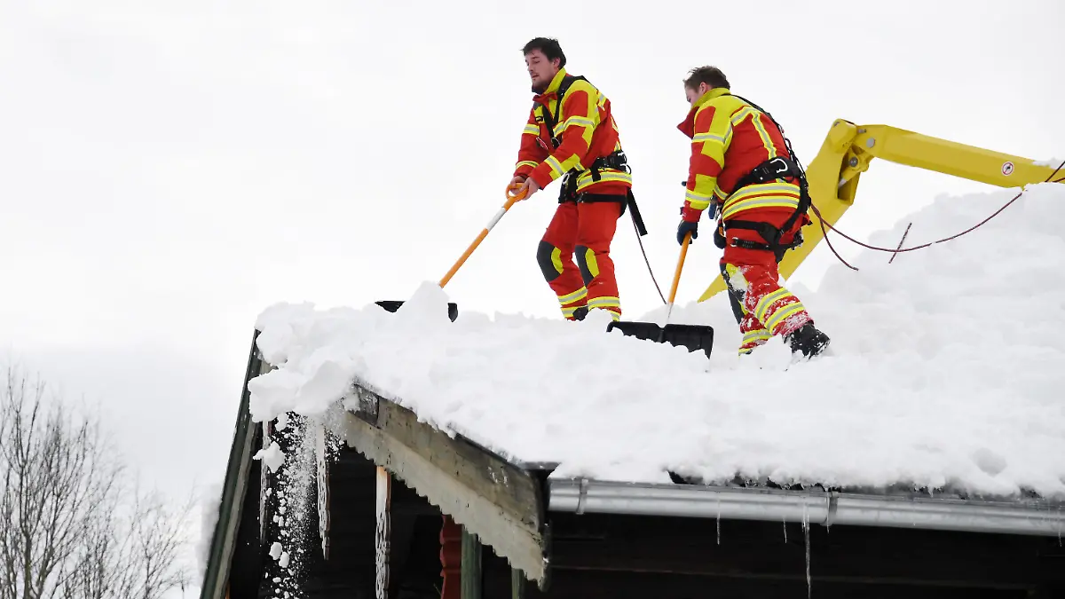 11.01.2019, Bayern, Inzell: Feuerwehrleute räumen den Schnee vom Dach eines Hauses. Die heftigen Schneefälle der vergangenen Tage halten in Südbayern weiter die Einsatzkräfte in Atem und neuer Schnee ist bereits im Anmarsch. Mehr als 1000 Helfer sind nach Behördenangaben in den südlichen Landkreisen von Oberbayern im Einsatz gewesen. Foto: Tobias Hase/dpa +++ dpa-Bildfunk +++