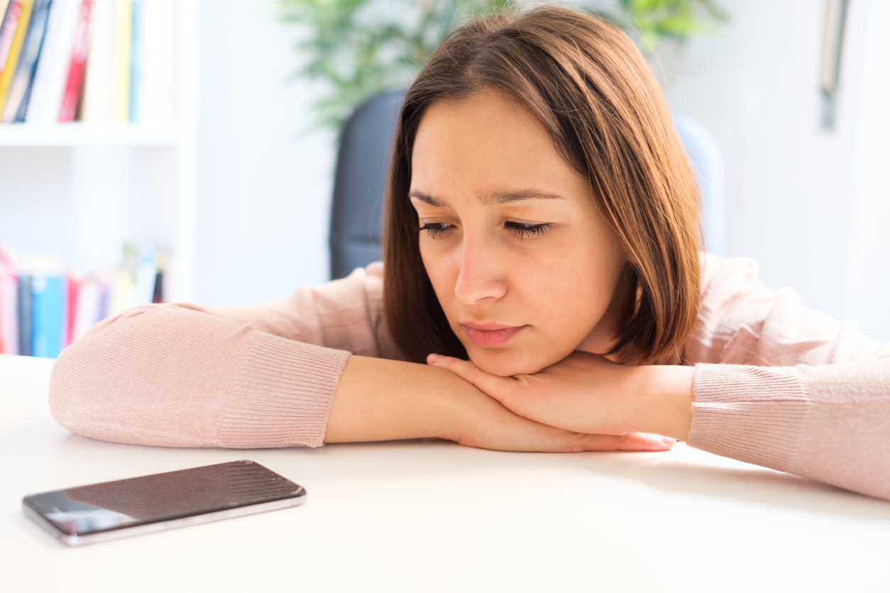 Traurige Frau schaut auf Ihr Smartphone