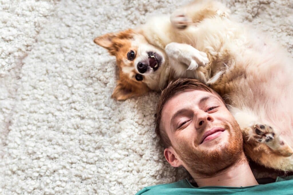 Hundehalterin sitzt mit ihrem Hund auf einer Wiese